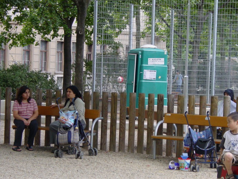 Frauen und Kinder sitzen auf einer PArkbank